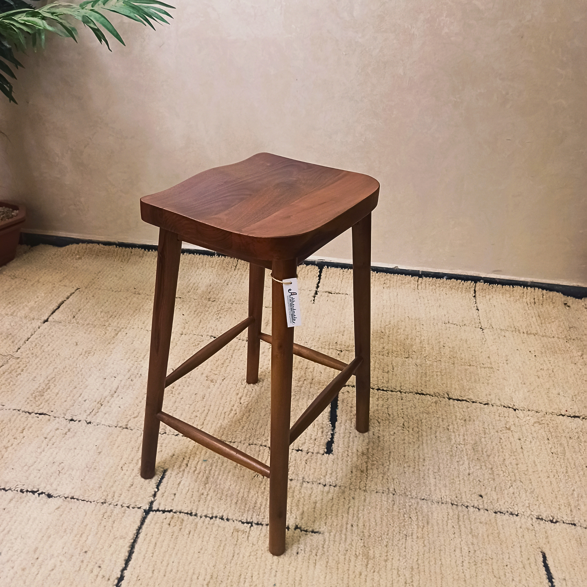 Wooden bar stool on a textured floor with a neutral wall background