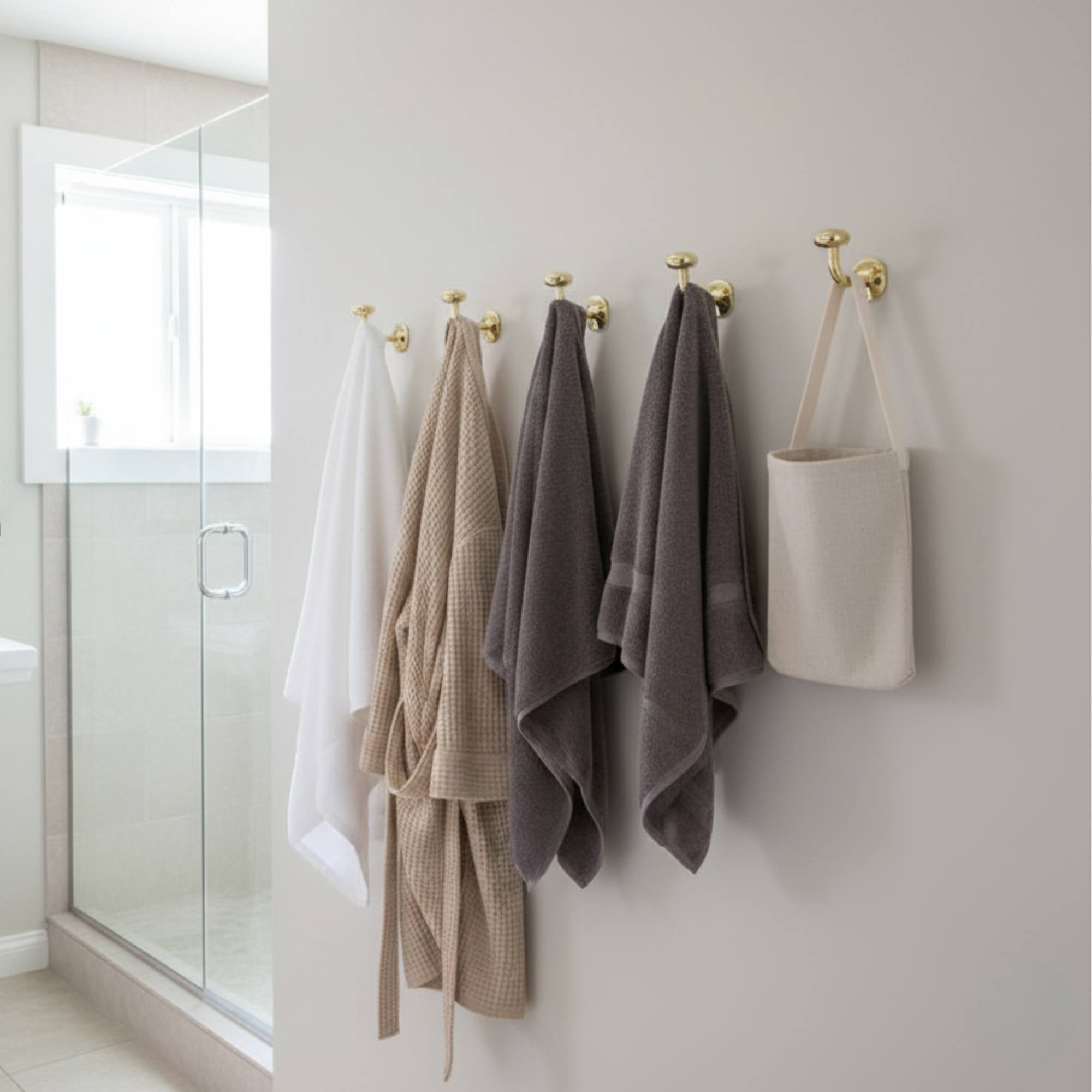 Towels hanging on hooks against a white wall in a bathroom.