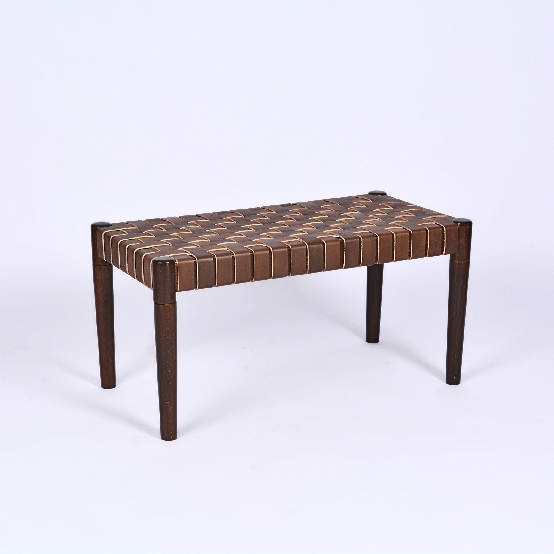 A woven leather bench with a brown teak wood frame, featuring a patterned design on the leather straps and a simple, elegant shape.