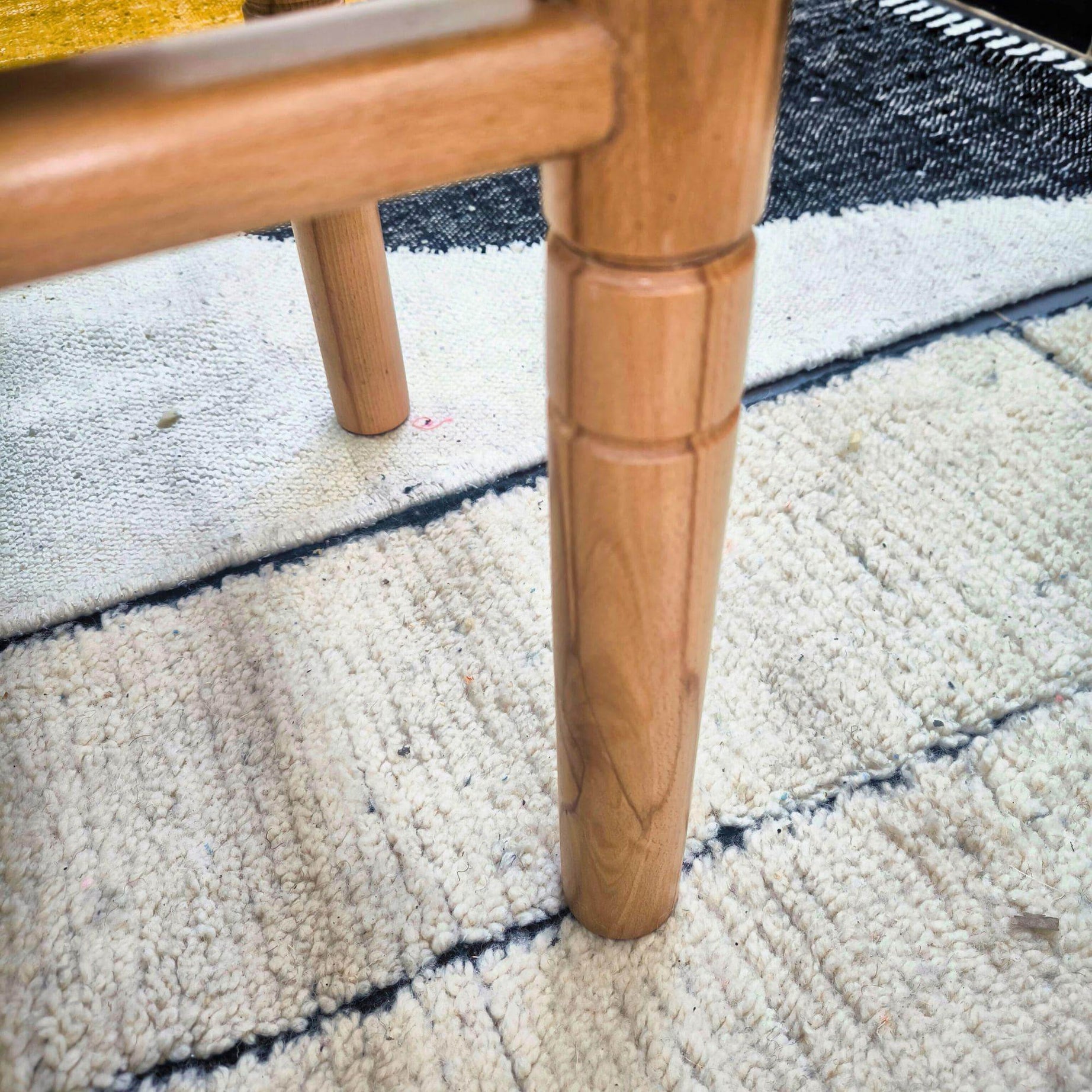 Close-up of a wooden bench leg on a textured carpet