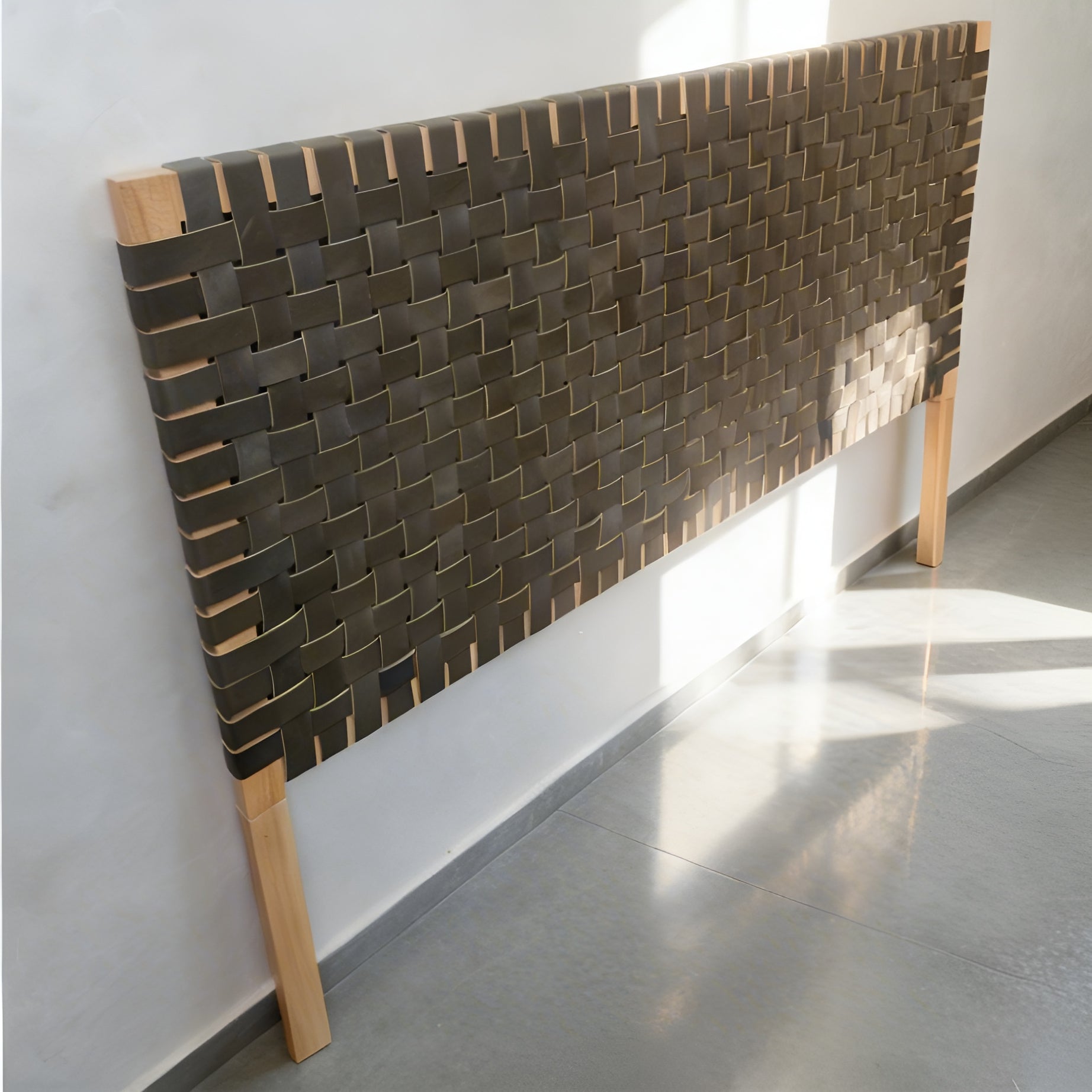Woven headboard with wooden frame against a white wall