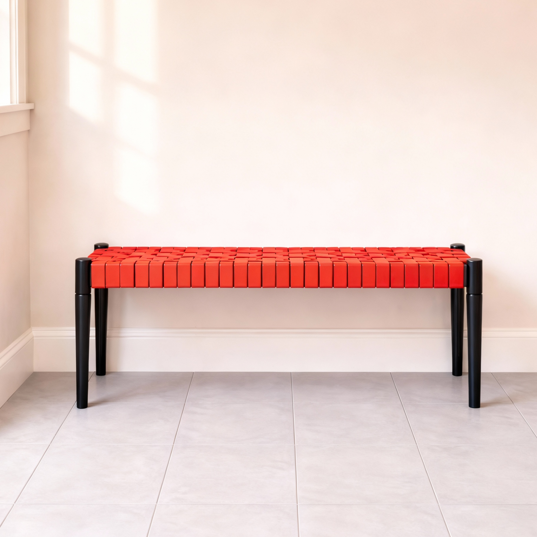 Red bench with black legs against a white wall