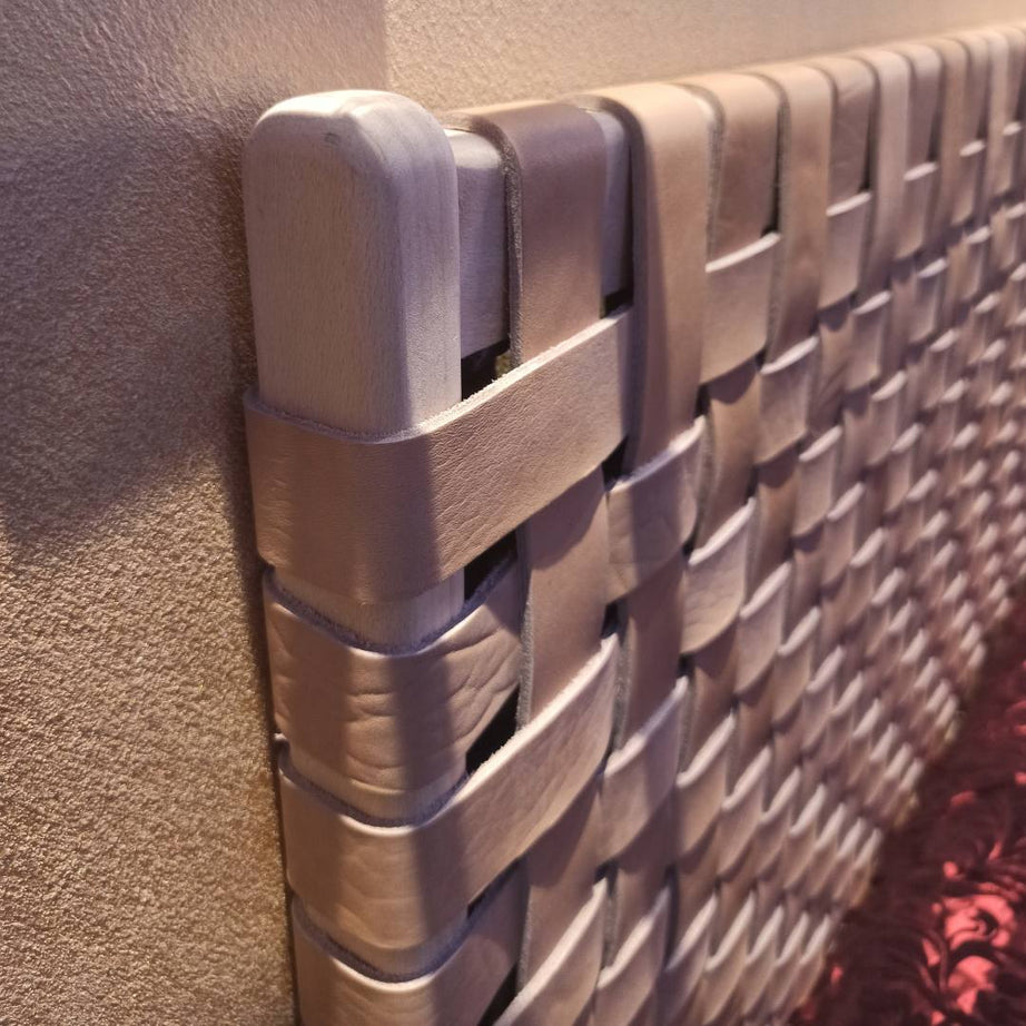 Close-up of woven straps on a handcrafted leather headboard, highlighting intricate artisanal weaving and texture.